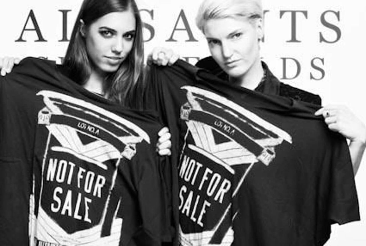 Black and white image of two celebrities holding a Not For Sale T-Shirt.