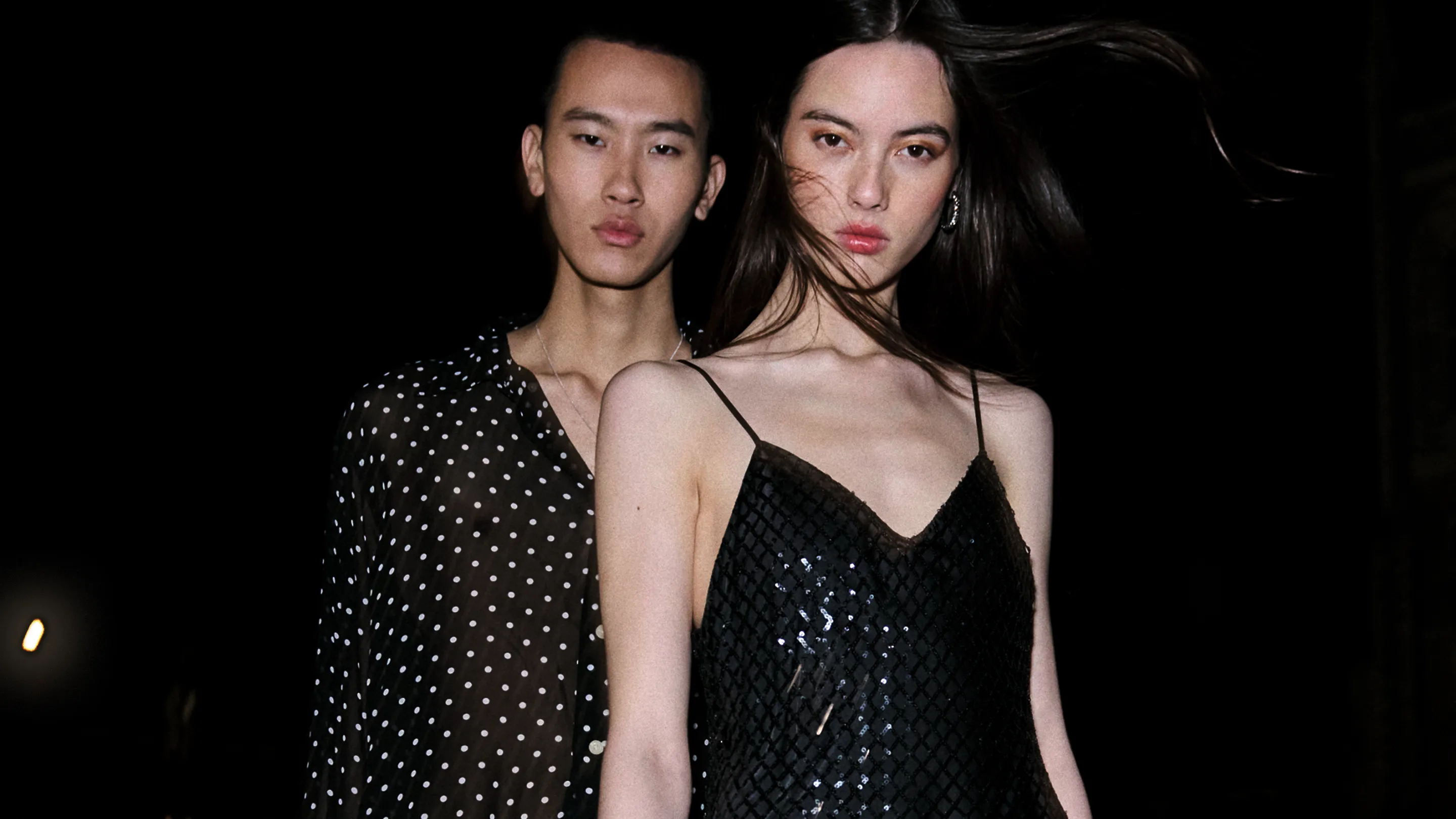 A male and female and male model sitting in the back of a car wearing black clothing.