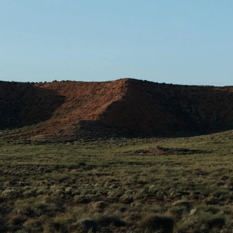 Photo of a hilled landscape with green grass in the foreground.