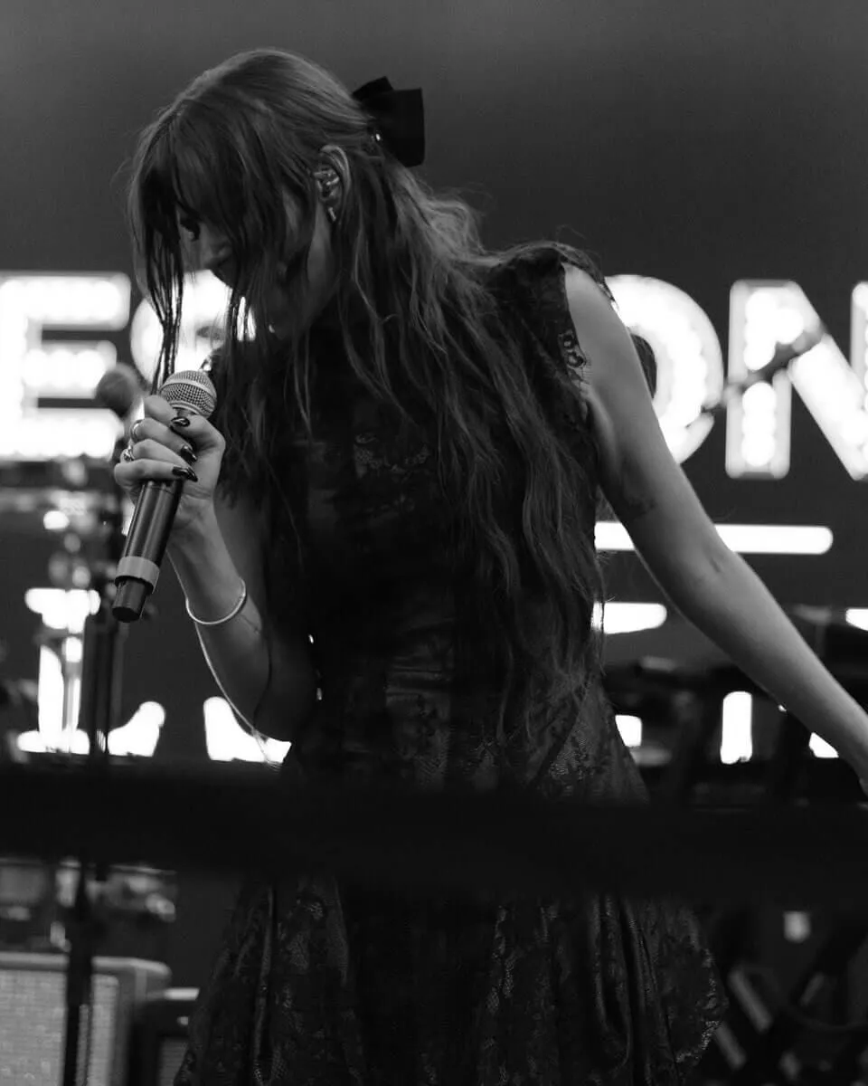 Women with hair covering her face as she sings into microphone