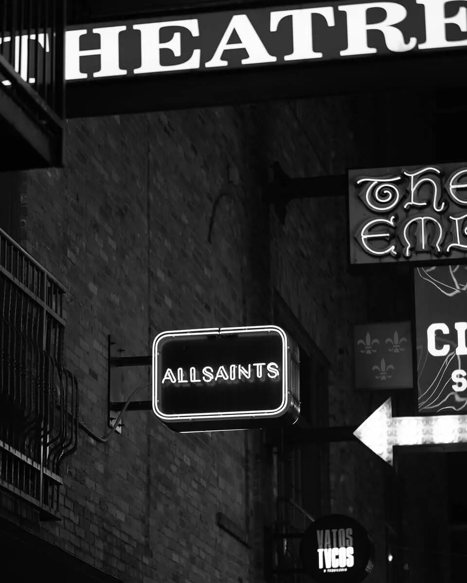 Black and white image of light up street sign that says ALLSAINTS