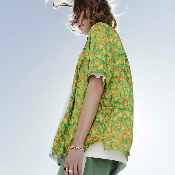 A man in the desert wearing a green print short sleeve shirt and jeans