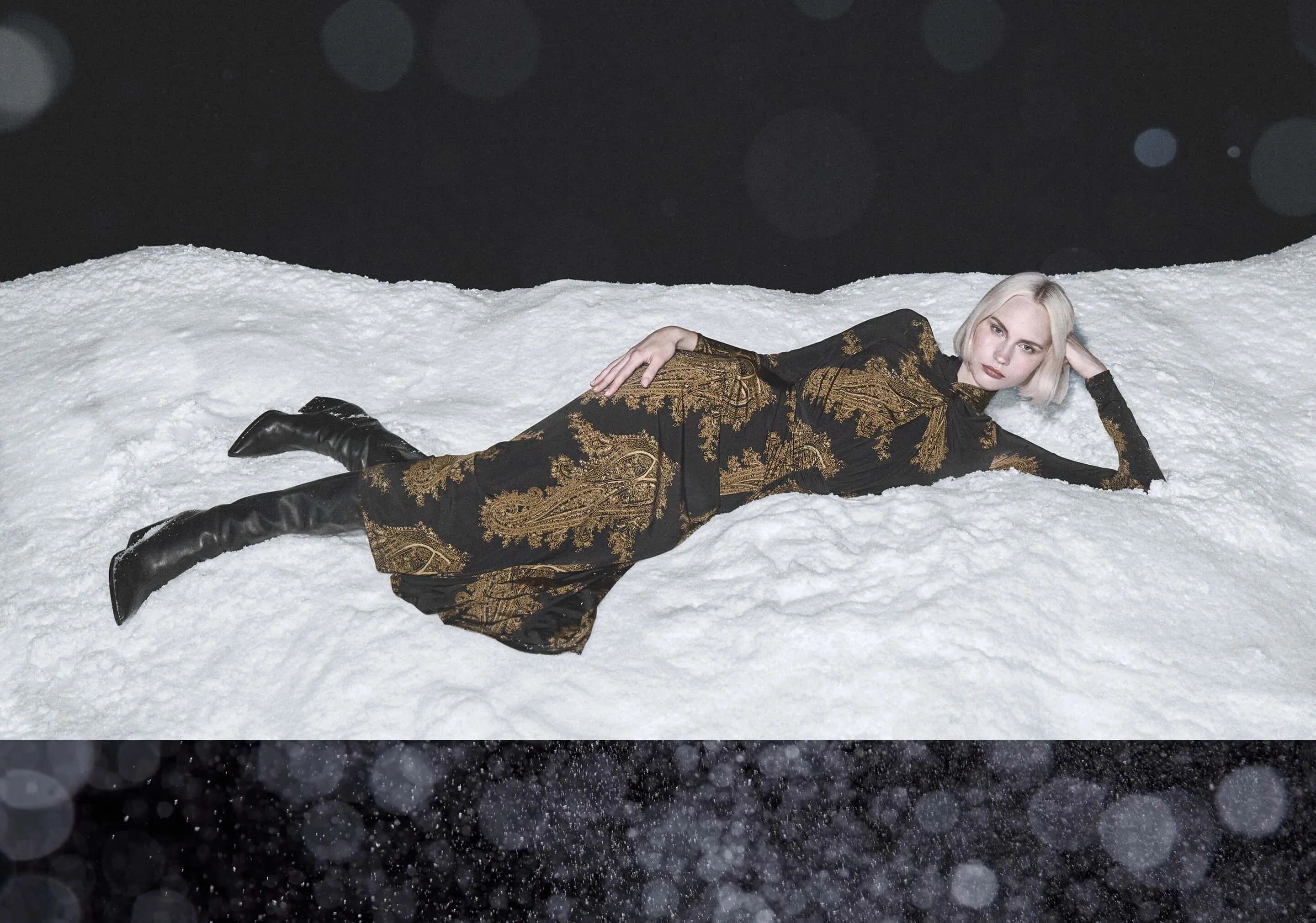 women swearing gold and black dress lying in the snow