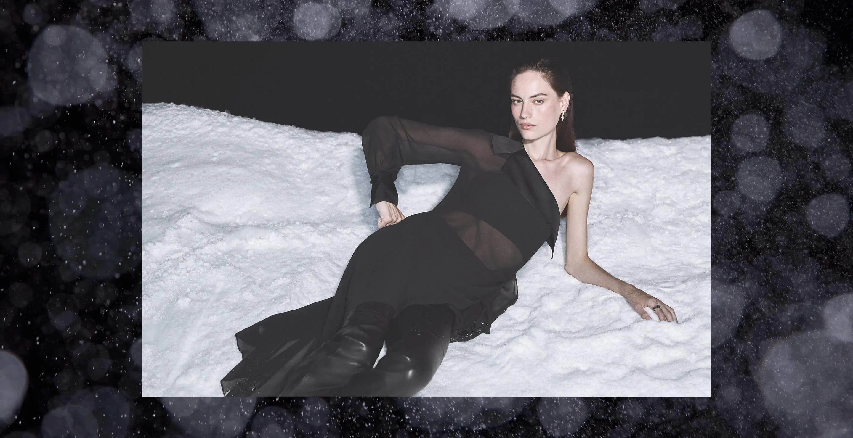 women lying on snow wearing black dress