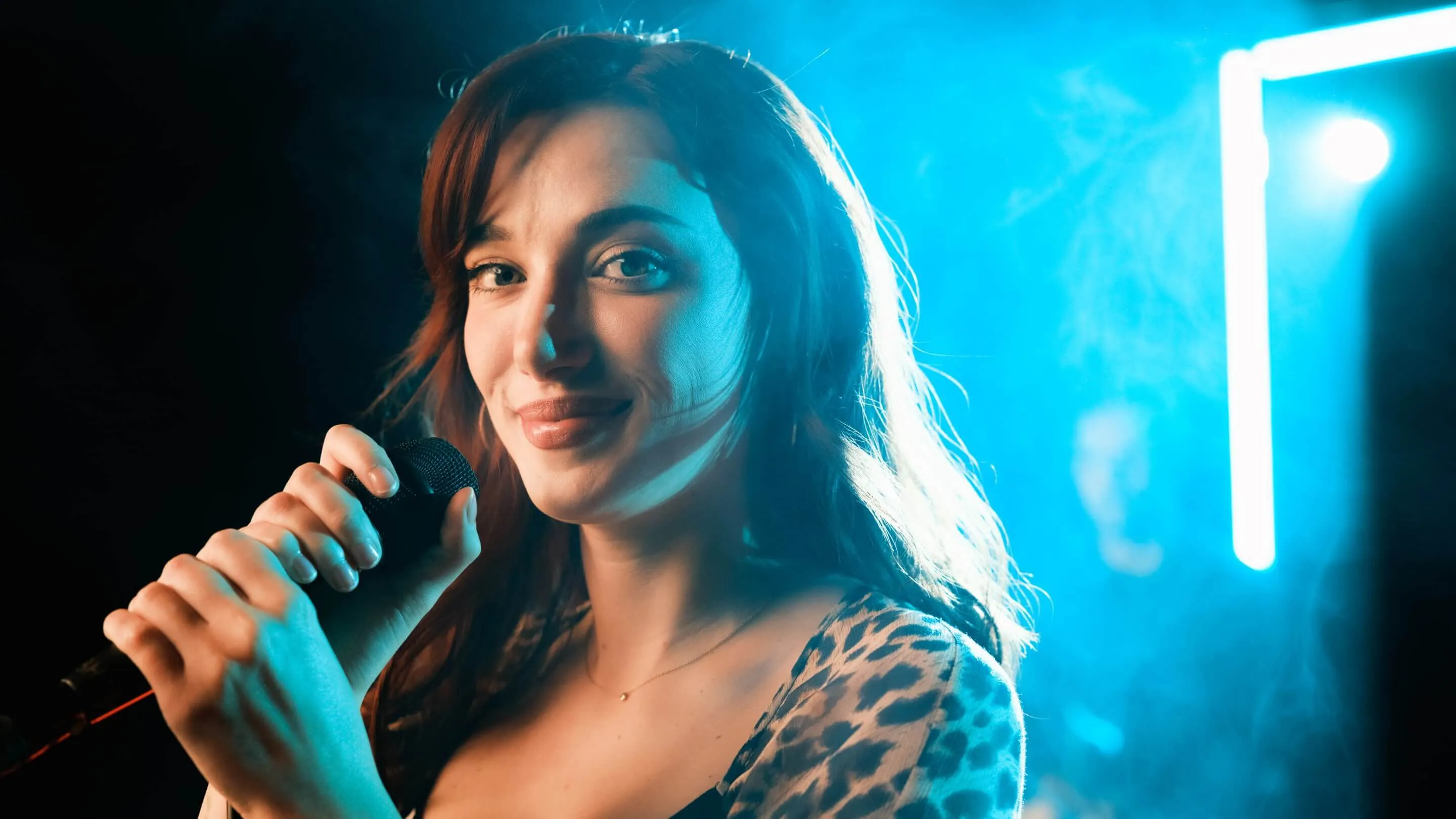 Closeup of Olivia OBrien holding the microphone and smiling.