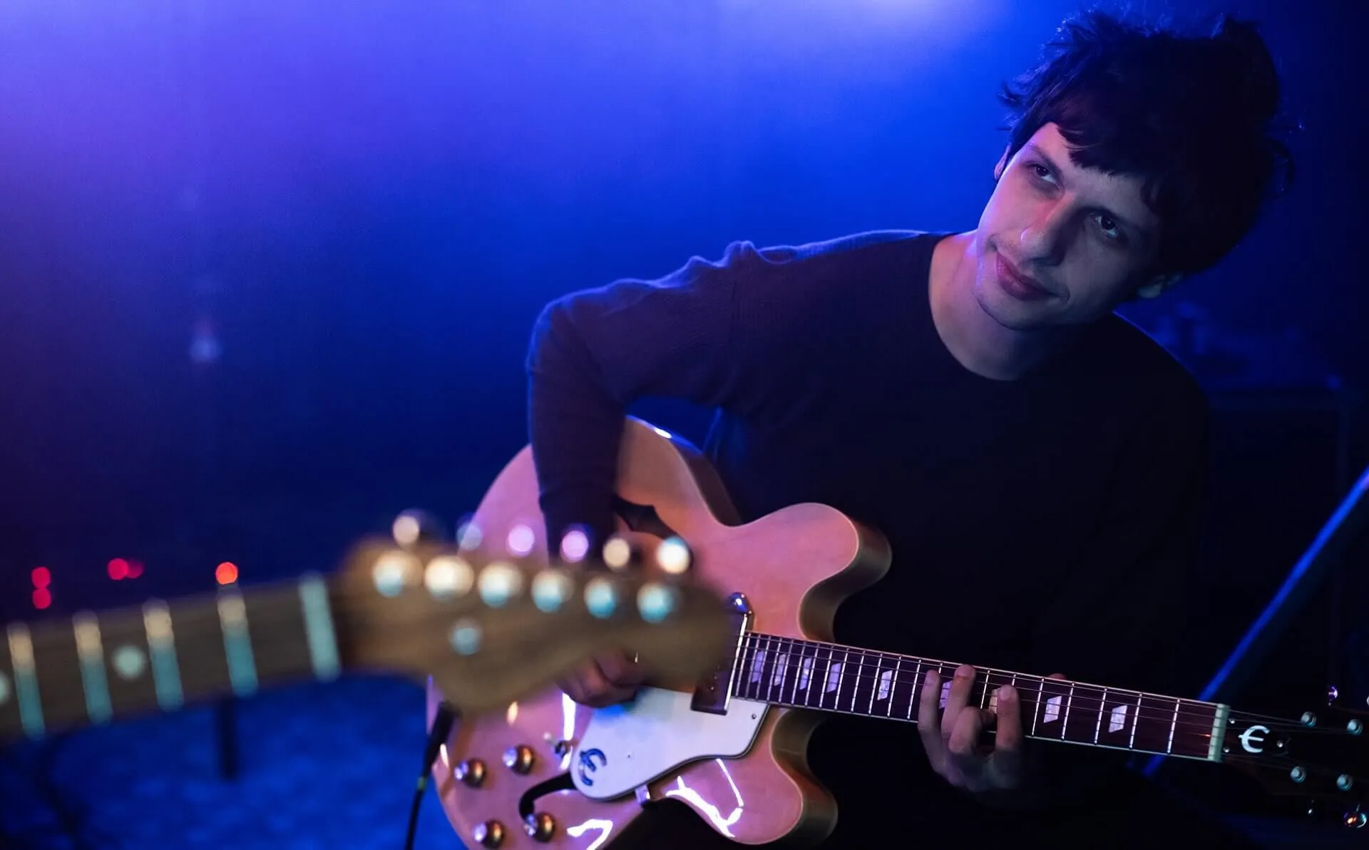 Guitarist on stage with blue background light.