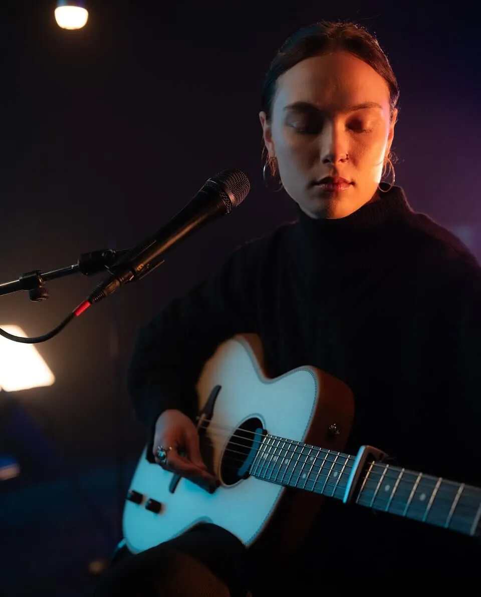 Abby Sage playing guitar on stage.