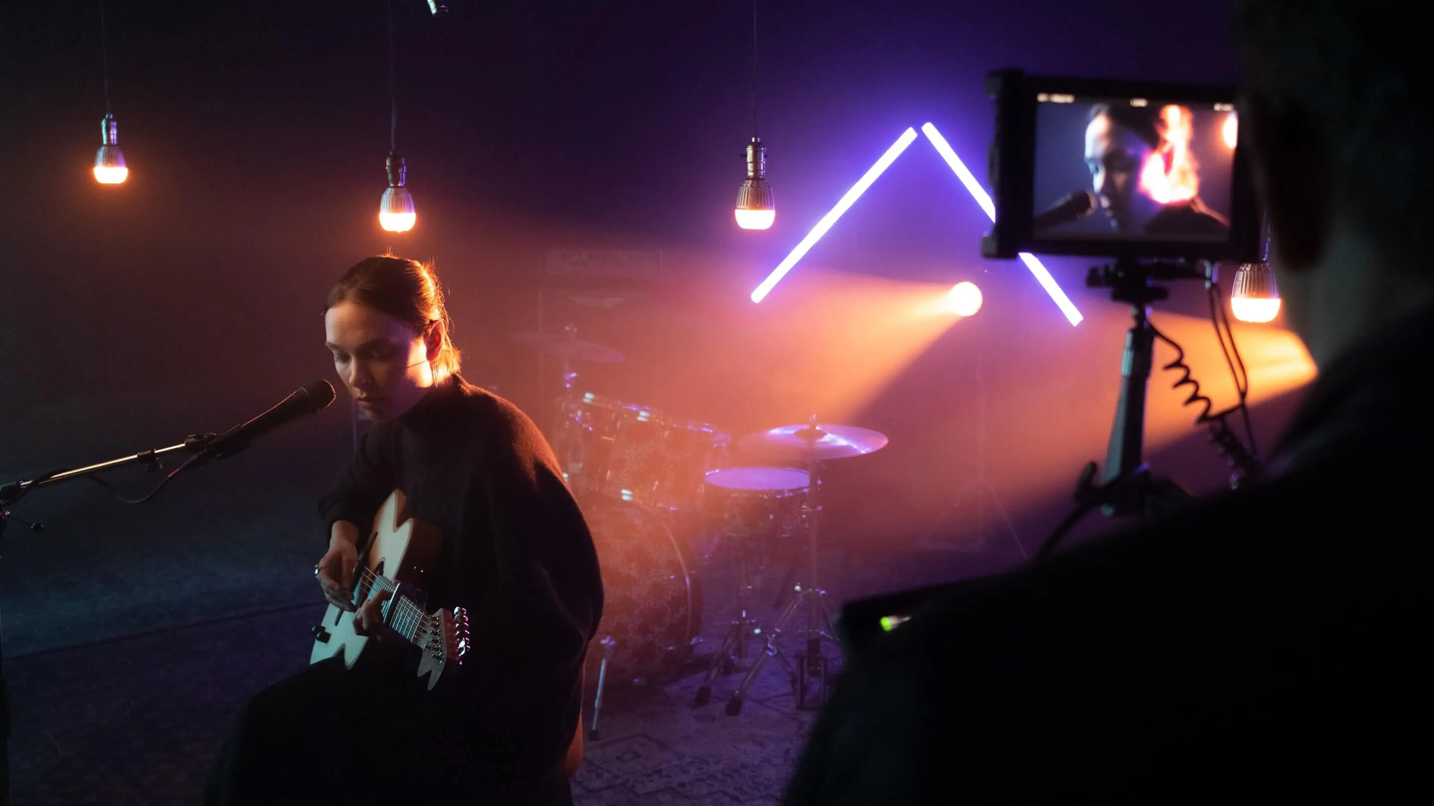 Photograph of Abby on stage being filmed singing into a microphone.