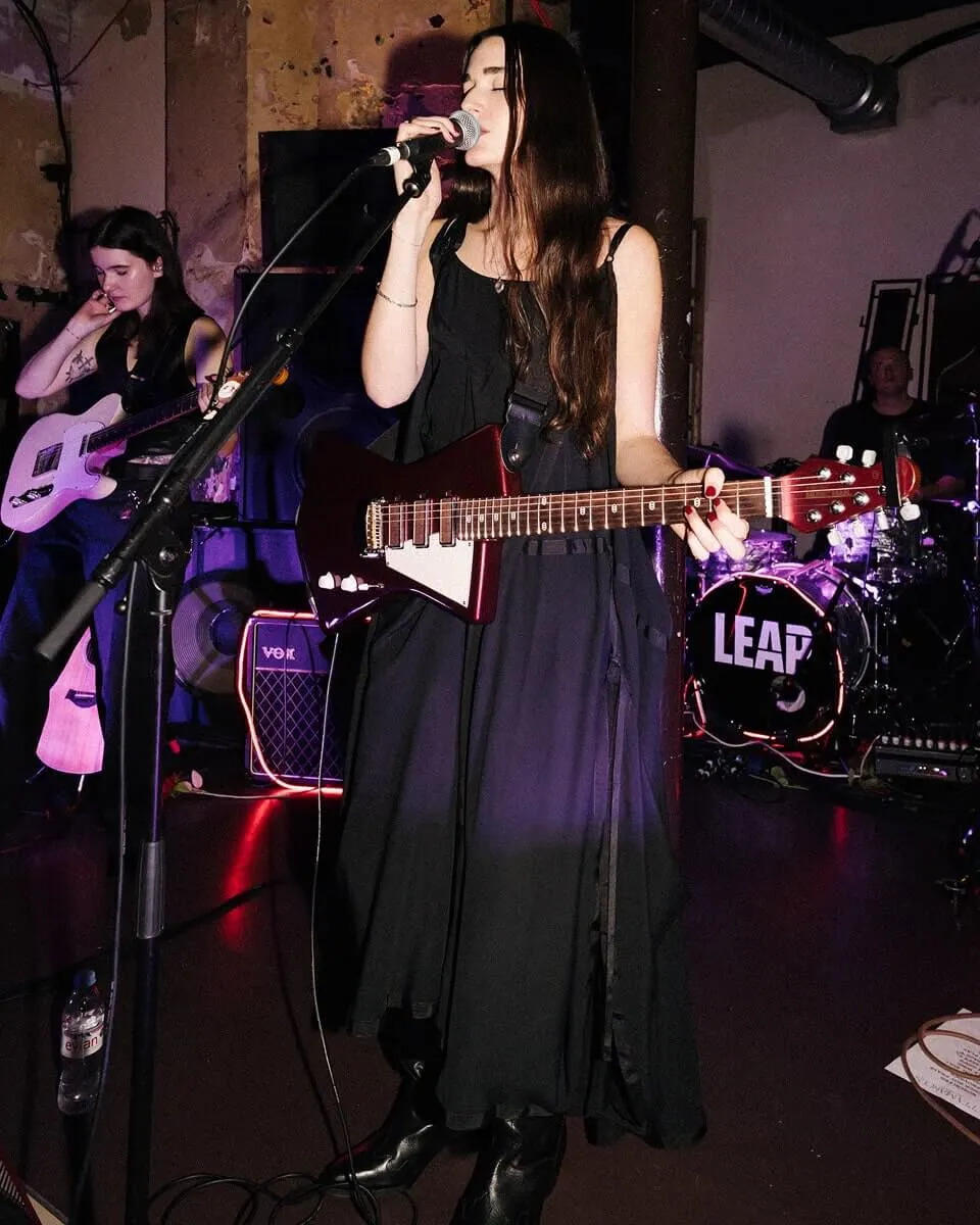 Full length shot of Etta Marcus standing on stage singing into a microphone.
