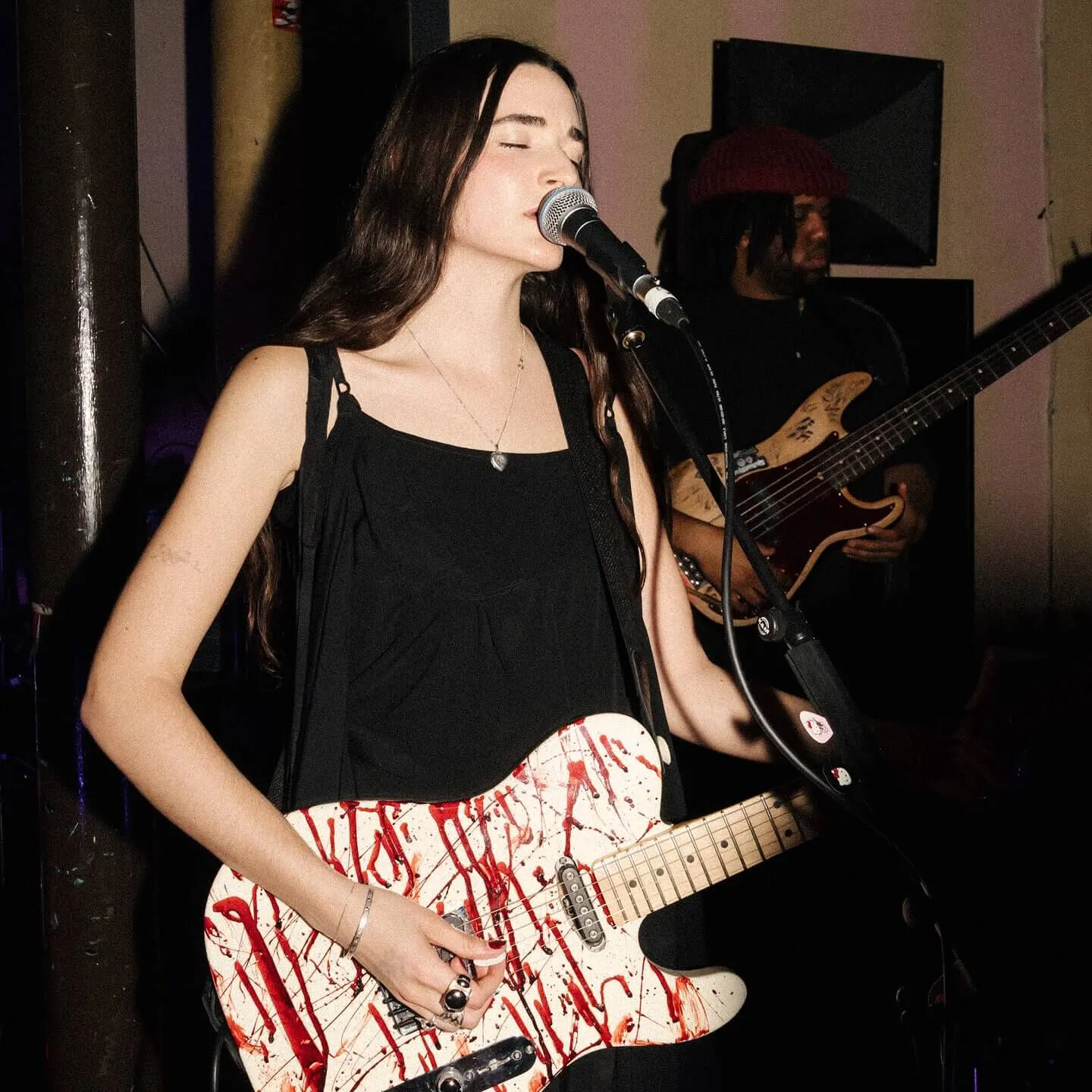 Closeup shot of Etta Marcus front singer on stage singing into a microphone with her eyes closed.