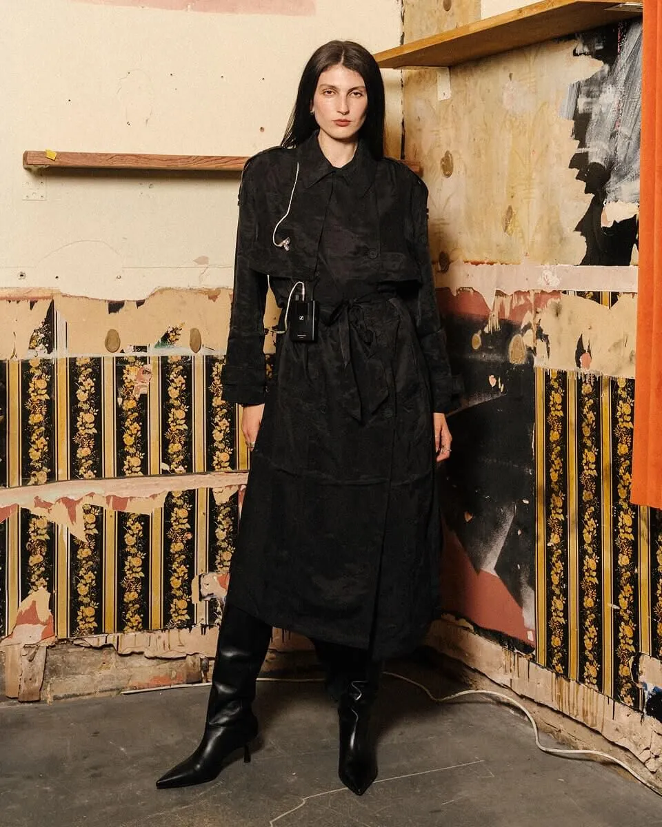 Black and whFulllength shot of Lucia & The Best Boys front singer posing infront of a wall for a photograph.