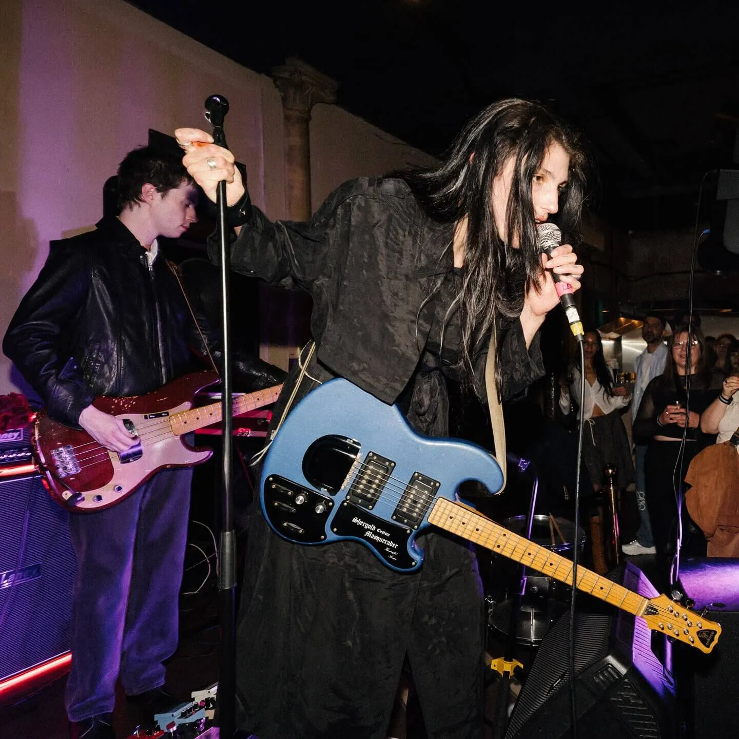 Closeup shot of Lucia & The Best Boys front singer on stage singing into a microphone.