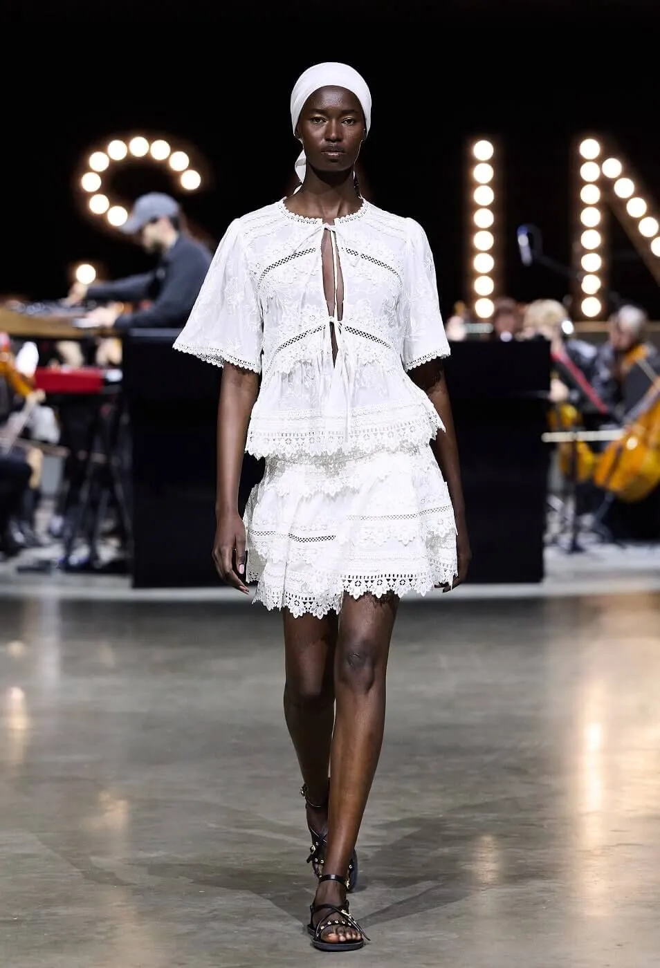 Woman wearing white skirt and top co-ord with lace trim