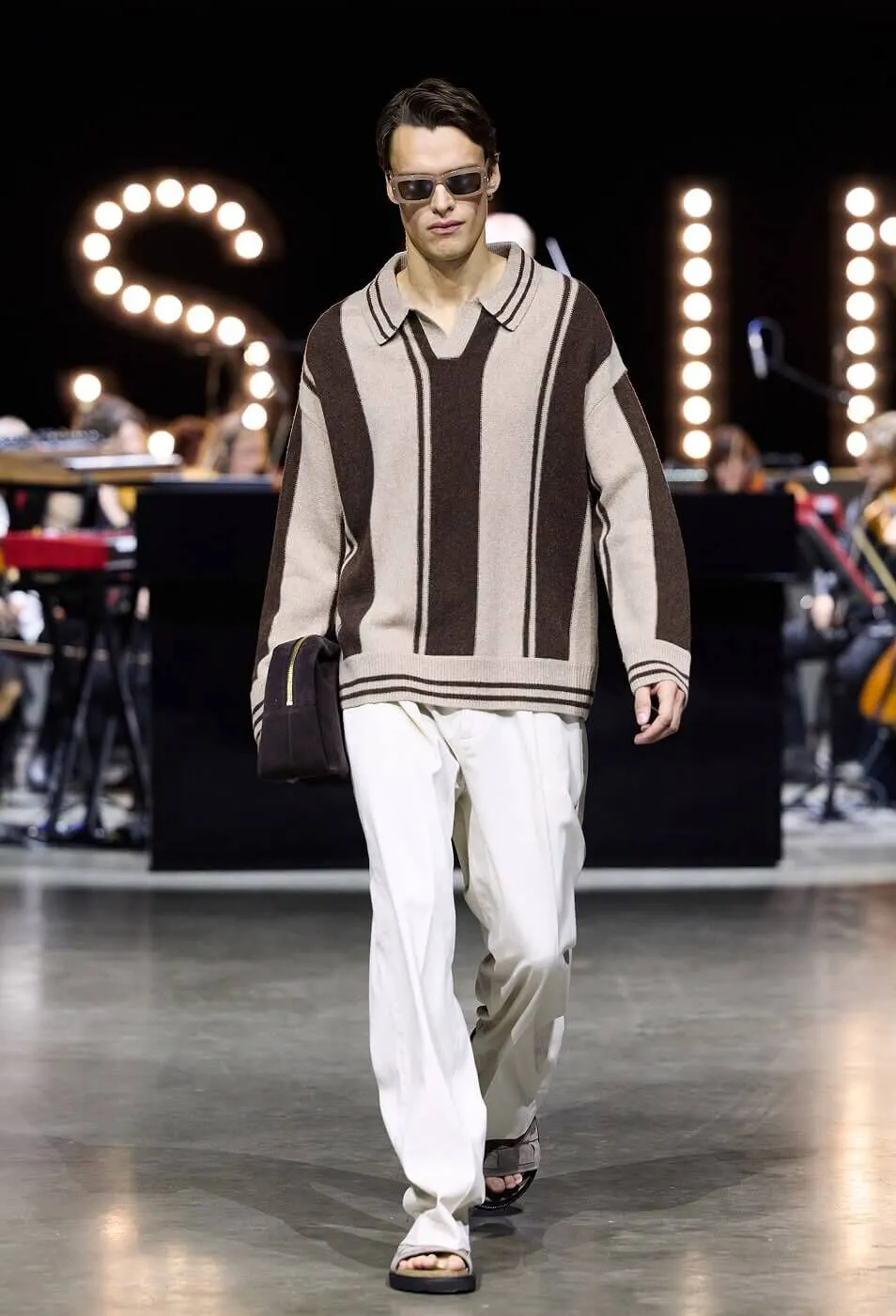 Man wearing striped collared jumper with white trousers