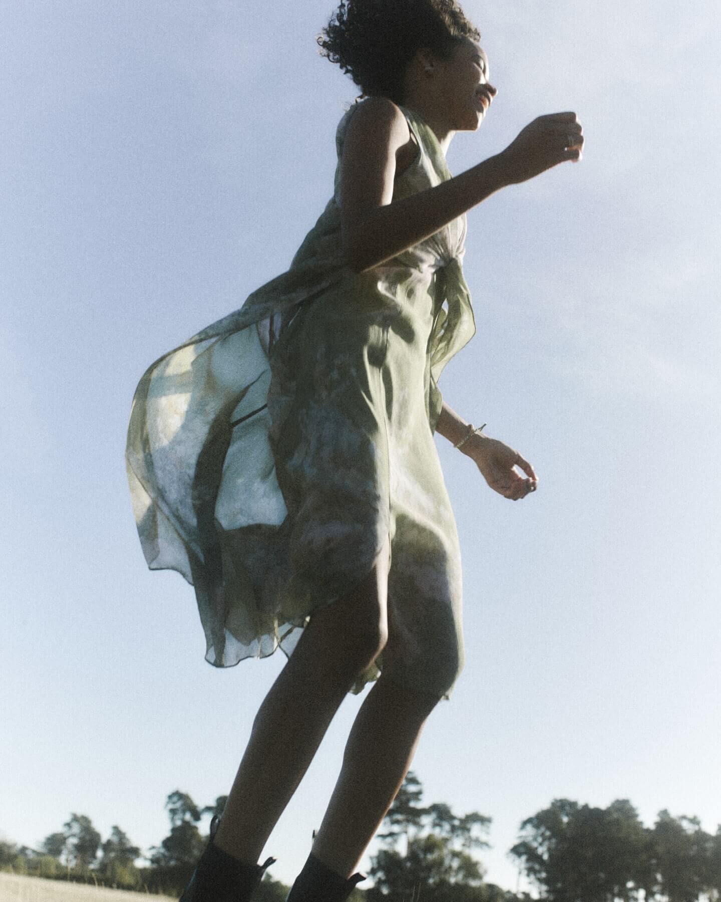 Woman wearing a floral dress swinging in the wind