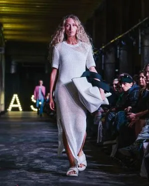 Woman wearing a maxi white mesh dress catwalking.