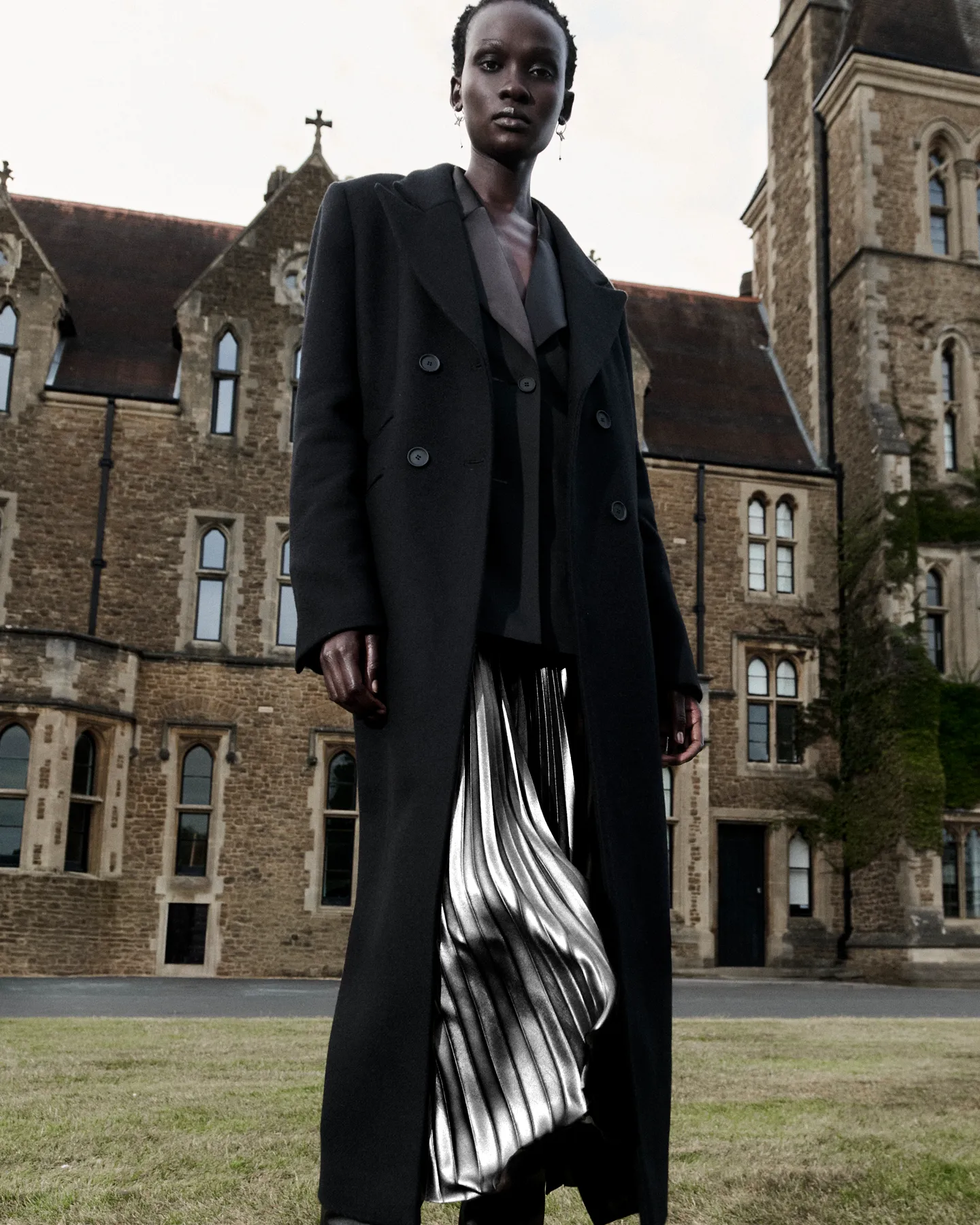 A woman wearing a long coat and mettalic dress.