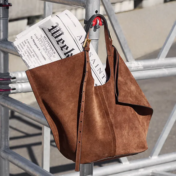 Woman wearing a denim shirt with a brown leather shoulder bag.