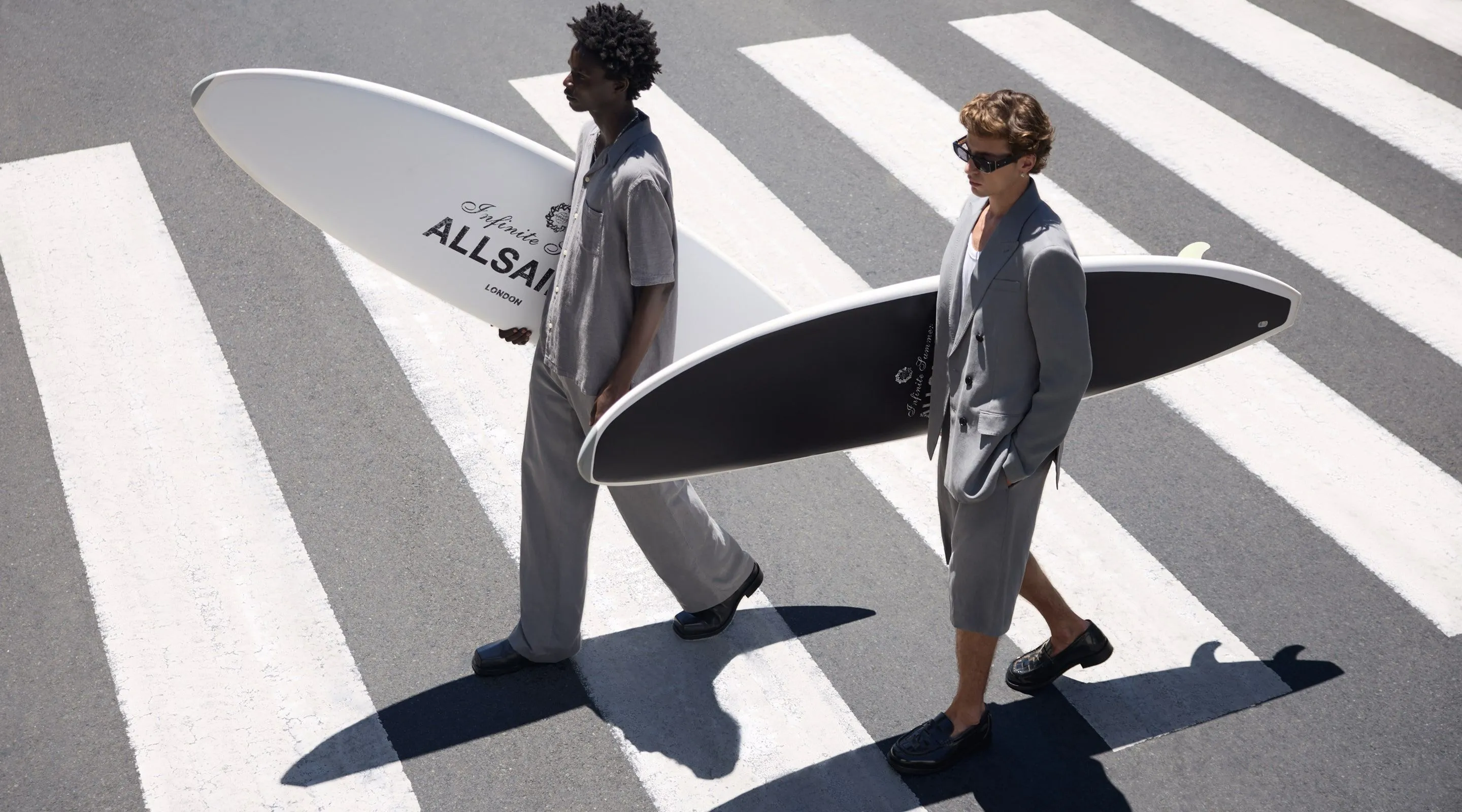 Two male models carrying surfboards