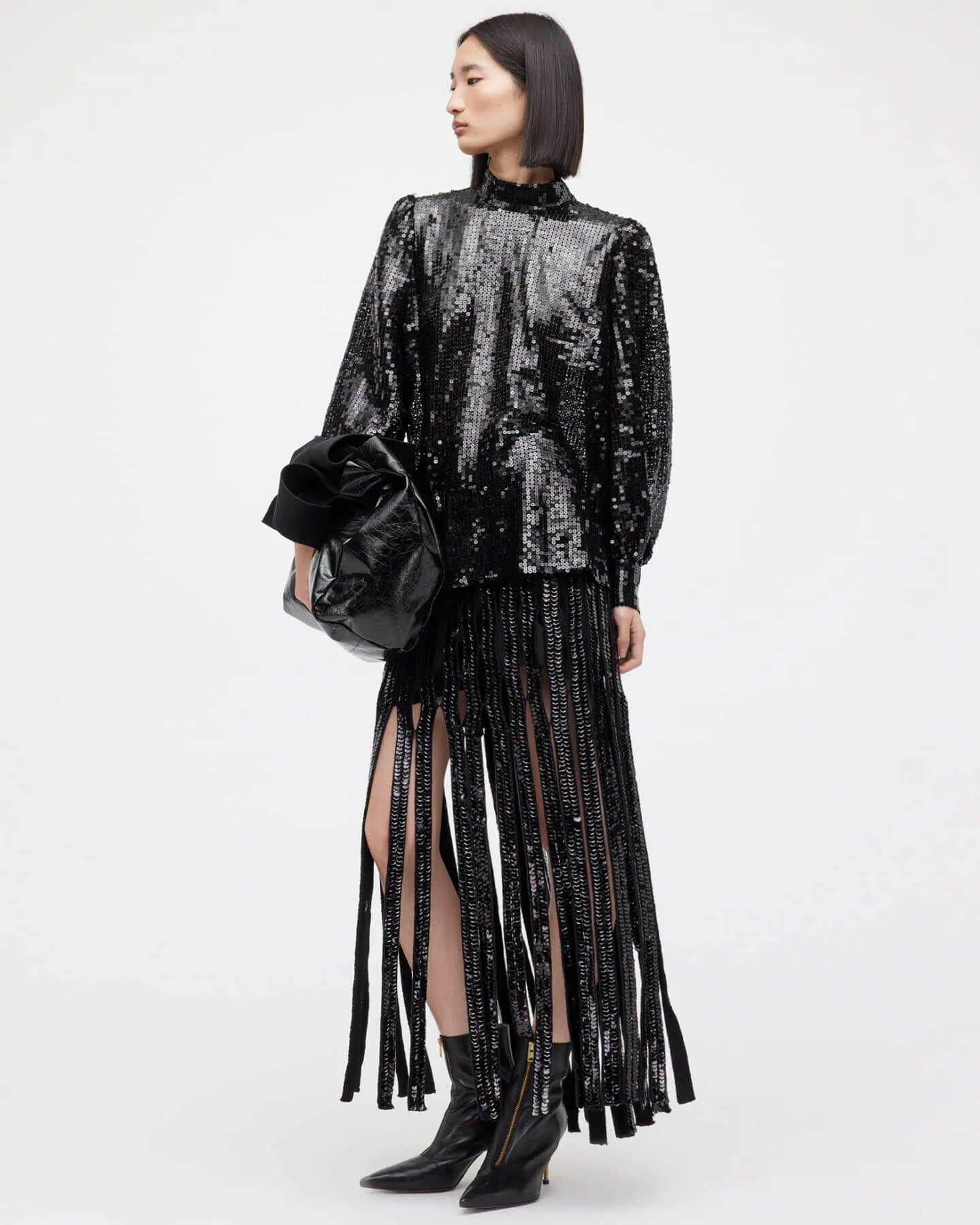 A woman wearing a black sequined top and sequin tassel skirt.