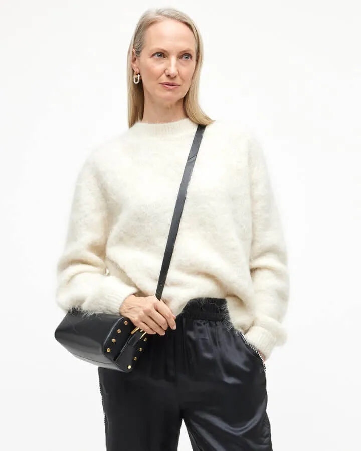 Model wearing a cream jumper and black trousers.