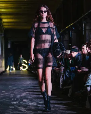 Woman wearing transparent black dress on a catwalk