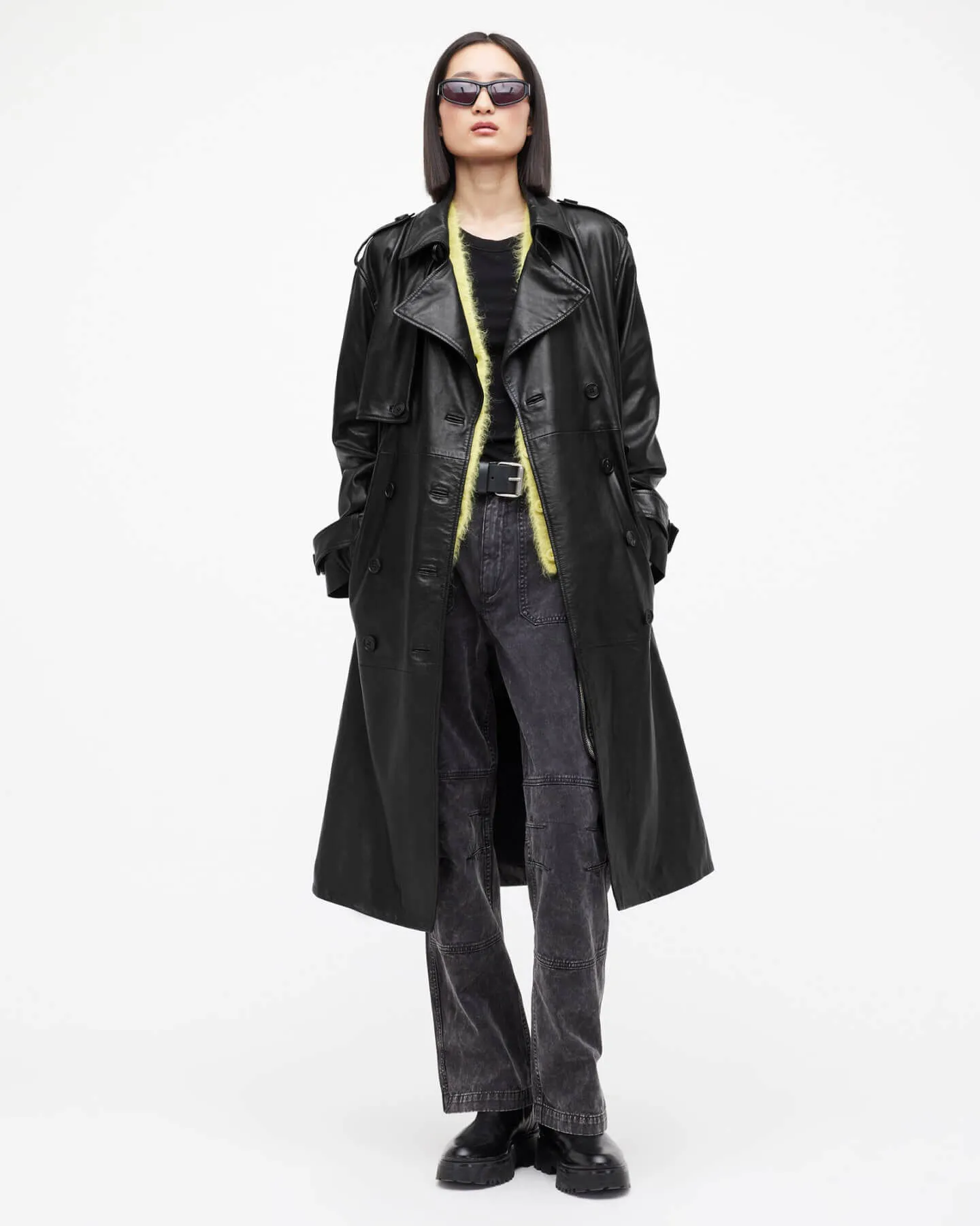 Woman wearing a long leather jacket and jeans.