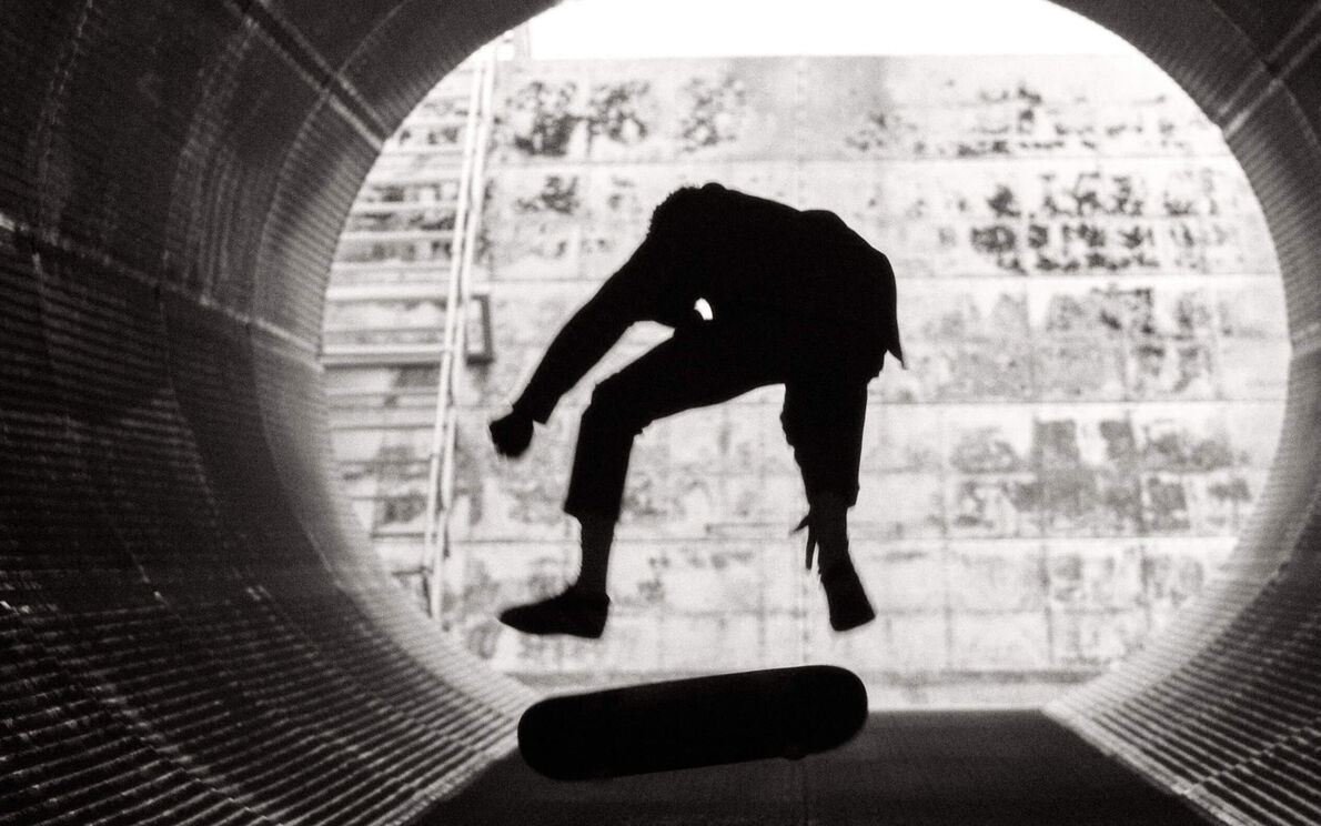 Man doing tricks on a skateboard in a metallic tube