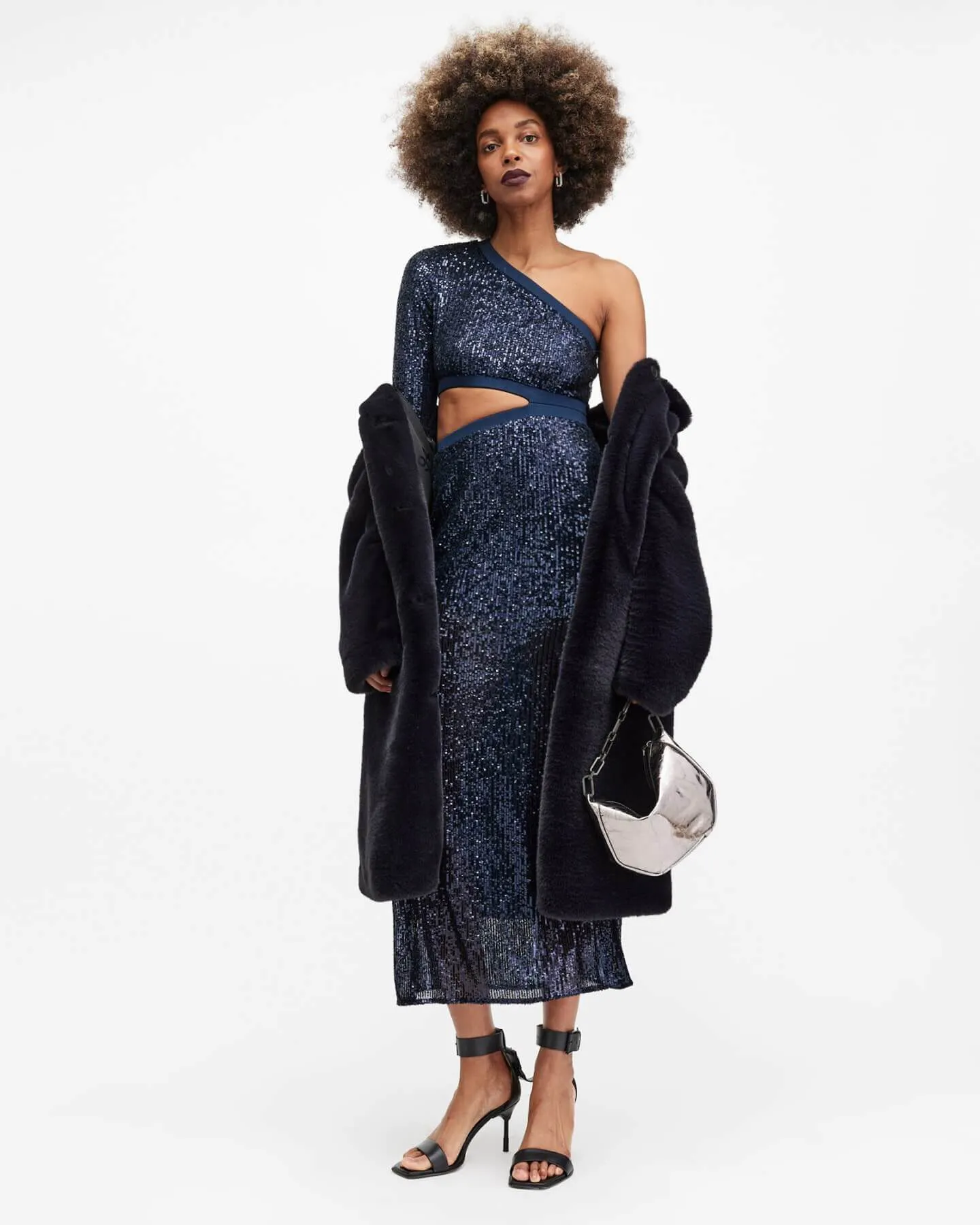 A woman wearing blue metallic dress and coat.