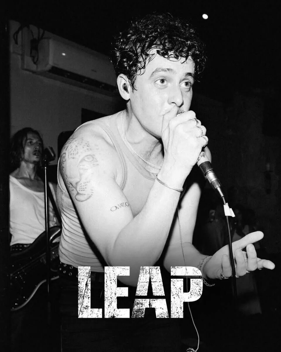 Black and white closeup shot of Leap front singer on stage singing into a microphone.